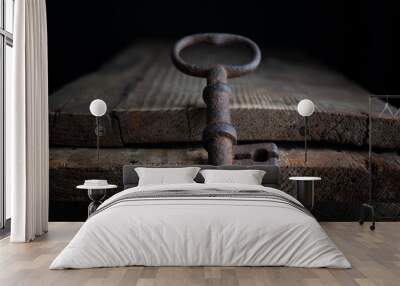 three old rusty keys stand on old wooden board against a dark background Wall mural