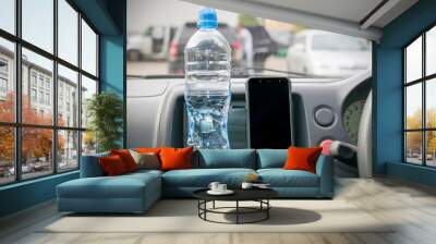 Smartphone and a bottle of mineral water on the car panel. Wall mural