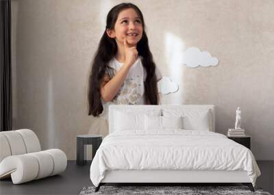 Portrait of a baby girl laughing against a wall background with clouds and sunlight. Wall mural