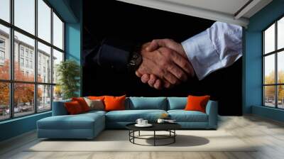 two male businessmen in black and white shirt shake hands, black background, studio shooting Wall mural