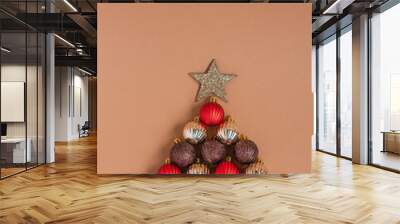 Christmas tree made of red, silver and brown balls on a beige background. Creative christmas concept. Wall mural