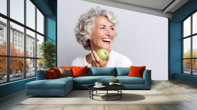 Beautiful cheerful smiling mature woman bites a green apple. Wall mural