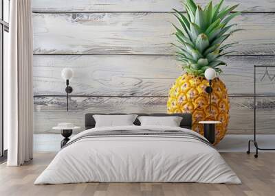 Juicy pineapple with a vibrant golden-brown skin and spiky green crown, freshly placed on a white wooden table. The pineapple's textured surface contrasts beautifully with the smooth, clean background Wall mural