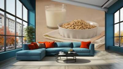 Oat flakes, cereal in a white ceramic bowl on a linen tablecloth on the table, a glass of milk, a spoon Wall mural