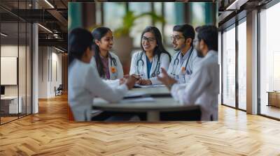 A group of doctors are sitting around a table, smiling and talking to each other Wall mural