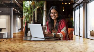 A woman is sitting at a table with a laptop in front of her Wall mural