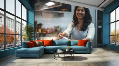 A woman is smiling and cooking food in a kitchen Wall mural