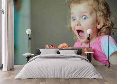 A young girl is holding a present and her eyes are wide open in surprise Wall mural