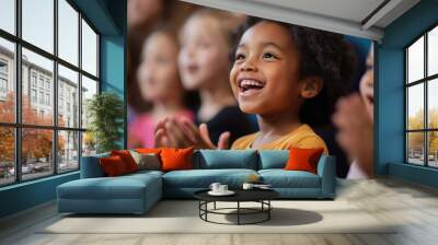 A young girl is smiling and clapping her hands in front of a group of children Wall mural