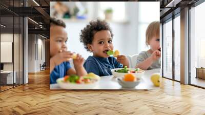 Three children are eating vegetables at a table Wall mural