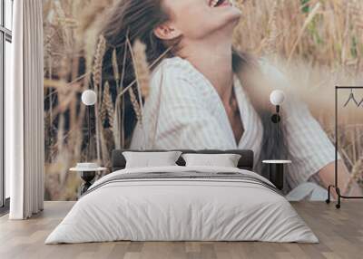 
portrait of a girl of model appearance in wheat, a girl sits in a wheat field and smiles Wall mural