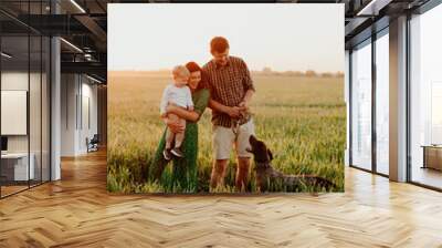 Happy family father and mother and child son whith dog walking on nature at sunset Wall mural