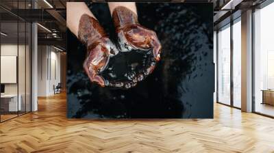 Hands are soaked in crude oil against the background of spilled petroleum products. The crisis of the oil industry. Economic downturn. Black gold. Copy space Wall mural