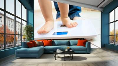 Closeup image of baby's feet standing on digital weight scales Wall mural