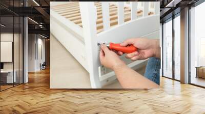 Closeup of handyman tightening the screws on white wooden bed Wall mural