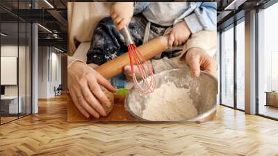 closeup of little baby boy kneading dough and flour in bowl for making bread with mother. concept of Wall mural