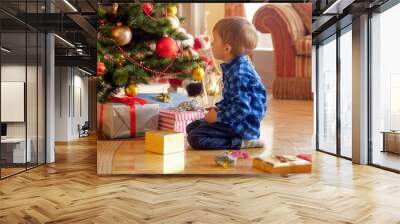 Little toddler boy looking on christmas tree at morning Wall mural