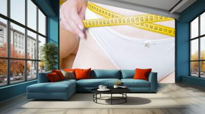 Sexy woman in panties measuring her waist with yellow measuring tape. Concept of overweight, weight loss and dieting Wall mural