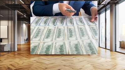 Successful businessman putting money on office desk while counting them Wall mural