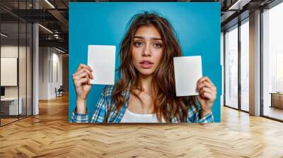 Beautiful young woman holding up two blank cards in front of her face. Wall mural