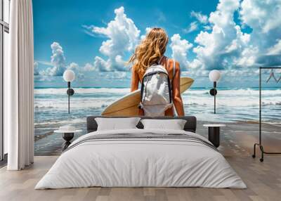 Woman walking on the beach with surfboard in her back pack. Wall mural