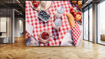 Picnic in the nature with croissants, peaches, strawberries, blueberries, grapes, baguette, cheese and glass bottles of milk Wall mural