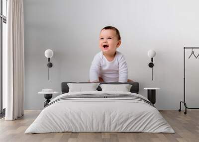 baby boy 9 months in a white bodysuit sitting on a white background, space for text Wall mural