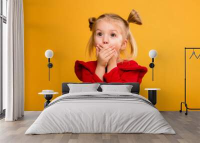 baby girl portrait isolate yellow background.Stylish little baby with hands up. Portrait of shocked little girl in red dress isolated on yellow background  Wall mural