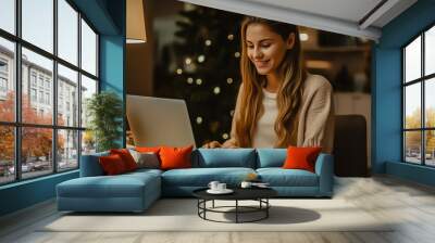 beautiful woman smiles, looks at her laptop, sits at home making online purchases gifts for the New Year Wall mural