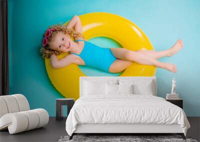 Cute girl in swimsuit holding swimming circle. Isolated on blue background .Summer holidays - pretty girl with inflatable ring  Wall mural