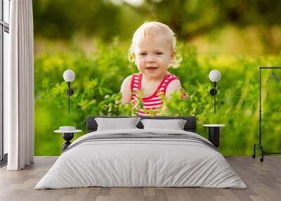 Cute little girl smiling in red summer dress walking on green lawn Wall mural