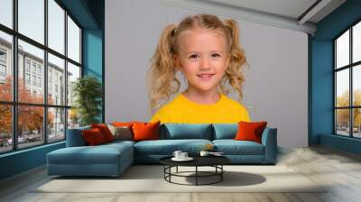 little blonde girl in yellow t-shirt smiling on light background, space for text Wall mural