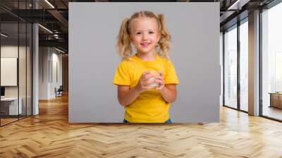 little blonde girl in yellow tank top holding a glass of milk on a light background, space for text Wall mural