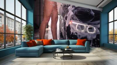 The girl in a bathing suit lying on the hood of car and washes it Wall mural