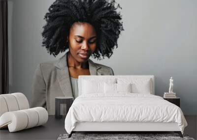 A woman with curly hair is looking at a tablet. She is wearing a jacket and a shirt Wall mural