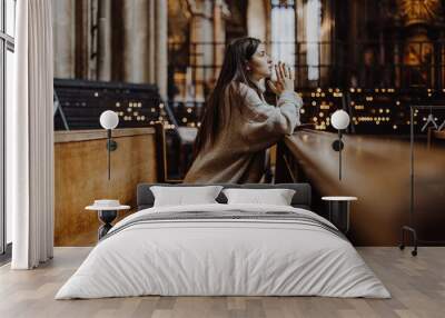 a woman praying on her knees in an ancient Catholic temple to God. copy space Wall mural