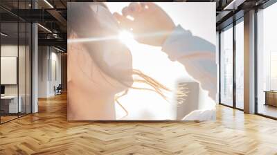 Back light portrait of a happy single hipster teen girl breathing fresh air at sunset in a park with a warm yellow light and urban background Wall mural