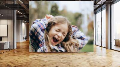 portrait of a happy and smiling little girl posing for a photo during a summer walk in the city Wall mural