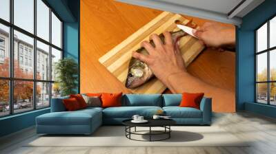 A woman is cleaning fresh fish perch on a cutting board Wall mural