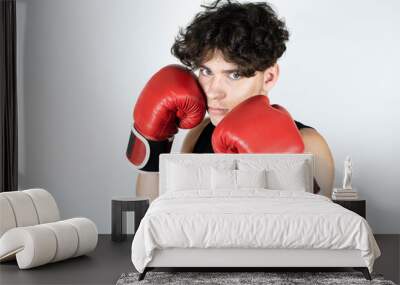 A handsome, athletic teenage boy in boxing gloves covers his face so that no one hits him. The concept of protection from life's troubles, problems Wall mural