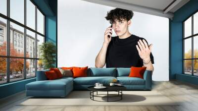 The teenage boy speaks expressively, emotionally on the phone at home, he proves to the delivery service that they are not high quality, untimely delivered food to his home Wall mural