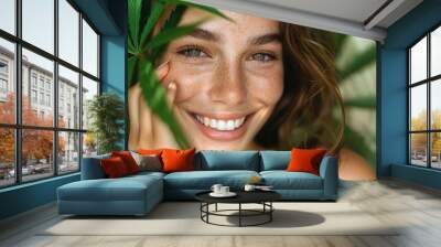 closeup portrait of pretty caucasian young woman smiling holding a marijuana leaf Wall mural