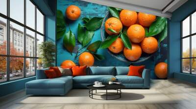 top view of oranges or tangerines and leaves covered with drops on blue wooden background Wall mural