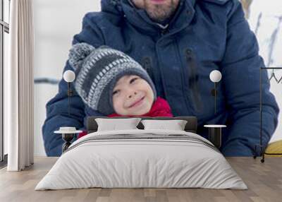 Father and son sledding in the snow in winter. Winter entertainment and recreation. The man and child are smiling into the frame. Warm clothes winter season Wall mural