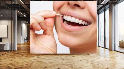 A cropped shot of a young beautiful caucasian woman brushes her teeth with a wooden toothpick after eating isolated on a white background. Oral hygiene, dental health care. Close-up. Dentistry concept Wall mural