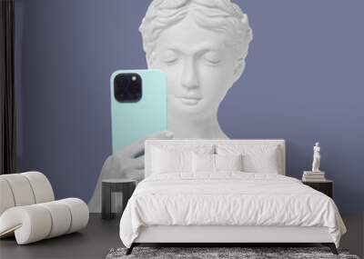 Antique female statue's head holding mobile phone with camera taking a picture or surfing Internet isolated on a violet background. 3d trendy collage in magazine style. Modern design. Contemporary art Wall mural