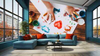 Close-up of child hand painting colorful mosaic. The child is drawing his palms on white sheets with finger paints Wall mural