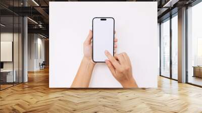 Mobile phone with white screen in female hands isolated on white background. Blank with an empty copy space for text. Mockup of smartphone for design. Young woman touching the screen with finger Wall mural