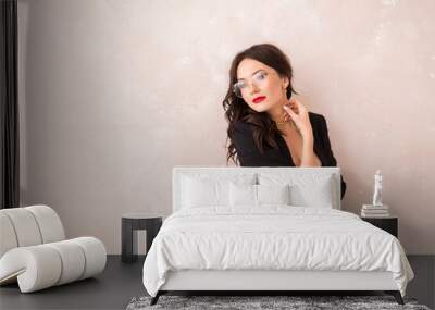 Portrait of a beautiful woman with glasses on a beige background. A girl in a black suit and glasses . Space for text Wall mural