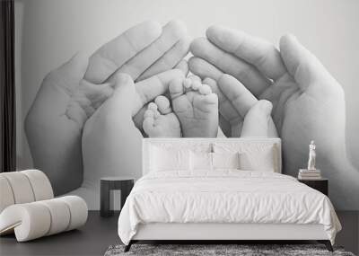 mother and father gently hold the baby's foot in their hands. Black and white image with soft focus on the baby's leg Wall mural